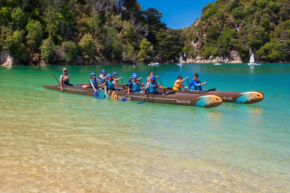 a double hulled waka with primary chool children at Kaiteriteri
