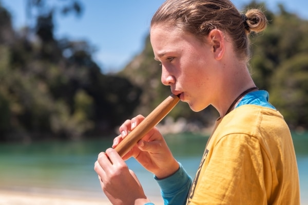 secondary school student playing a taonga pouro at Kaiteriteri