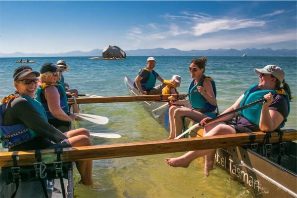 People in a double hulled waka at Kaiteriteri laughing